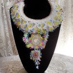 Plastron Envolée Fleurie Haute Couture brodé avec des cabochons Nacre et Résine aux couleurs Fuchsia et Ivoire, s’ajoute des fleurs lucites, feuilles en verre, chatons et perles en Cristal.